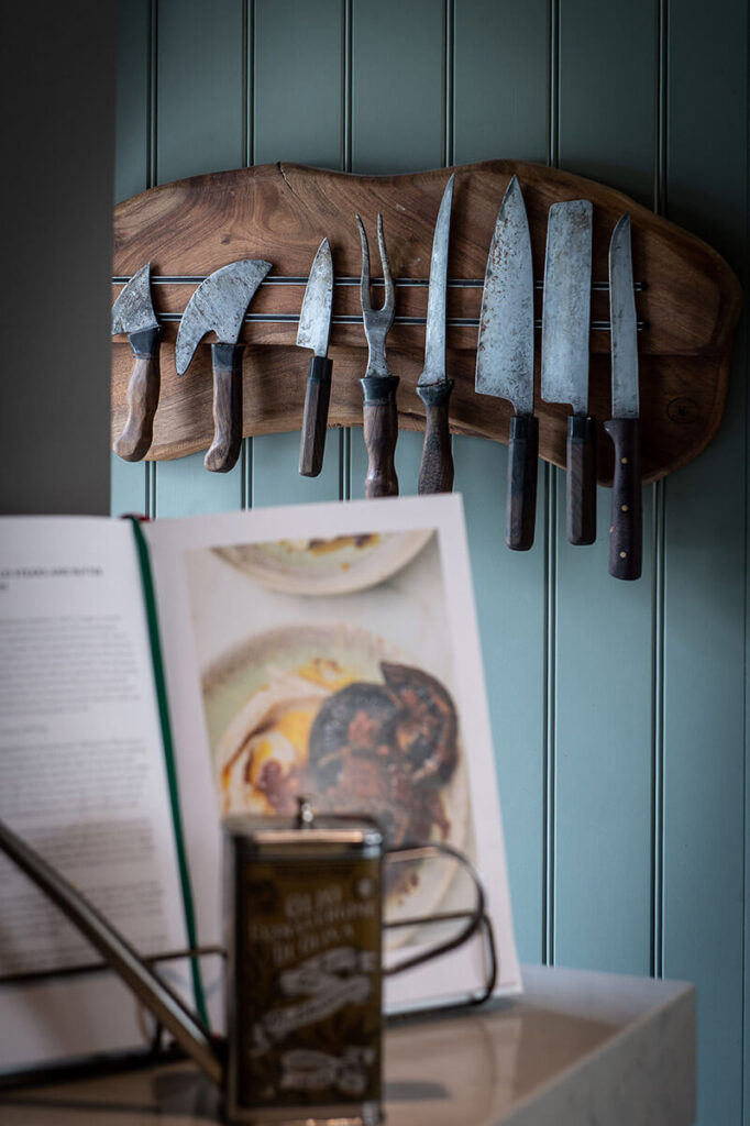 A set of antique knives hanging on the side of larder cabinet