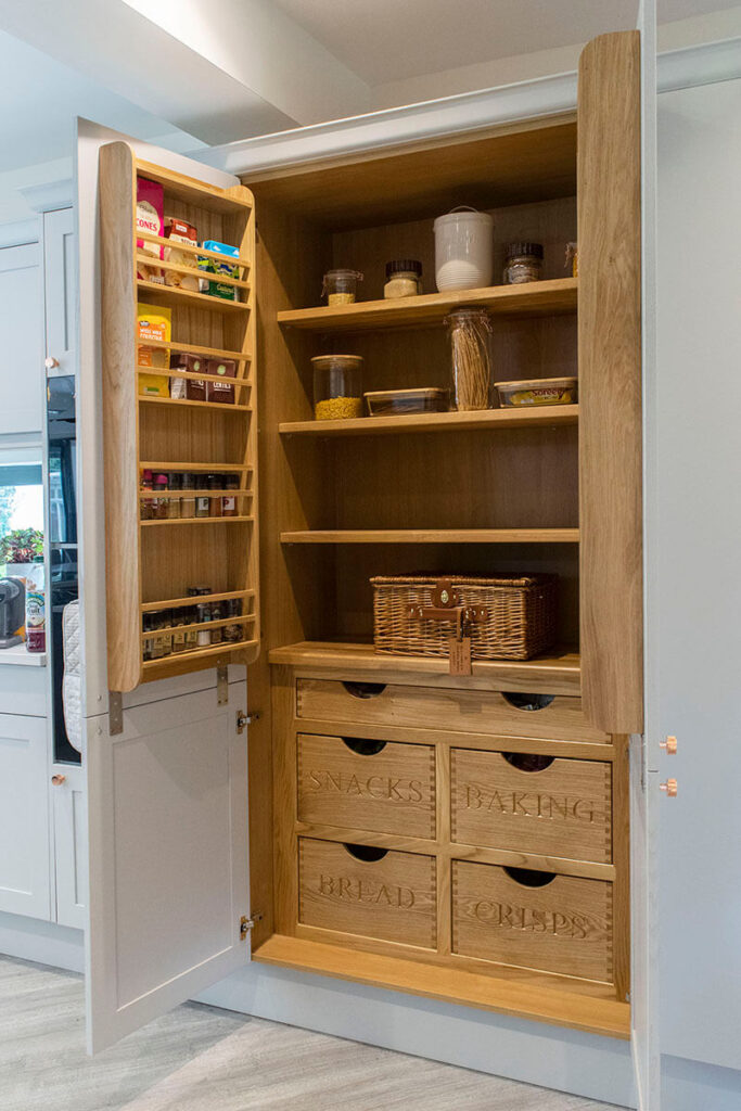 The bespoke pantry which when opened, reveals some beautiful natural wooden shelving and storage units with wording chosen by the customer