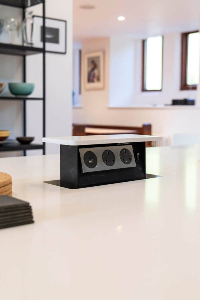 This pop-up power socket, integrated within the kitchen island allows for a sleek and convenient place to charge appliances