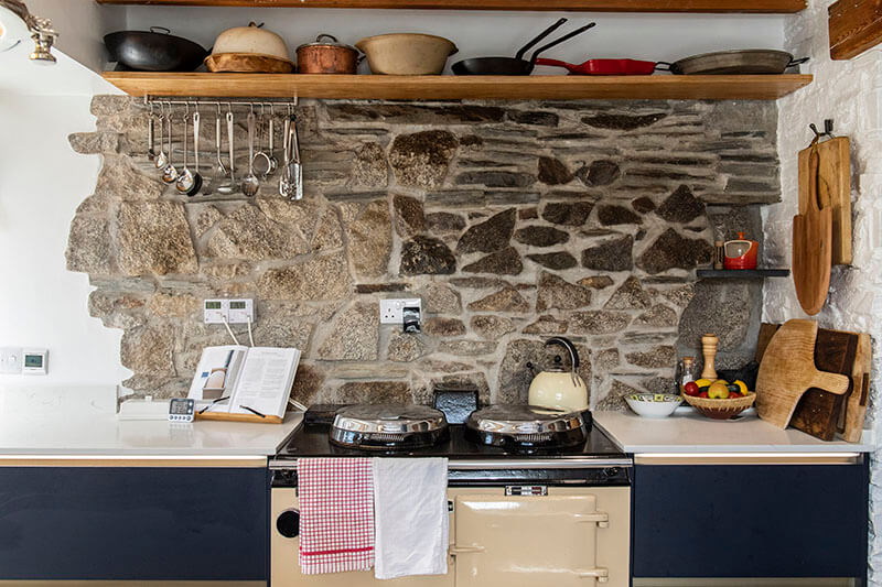 A rustic country kitchen with modern handleless navy blue kitchen cabinets