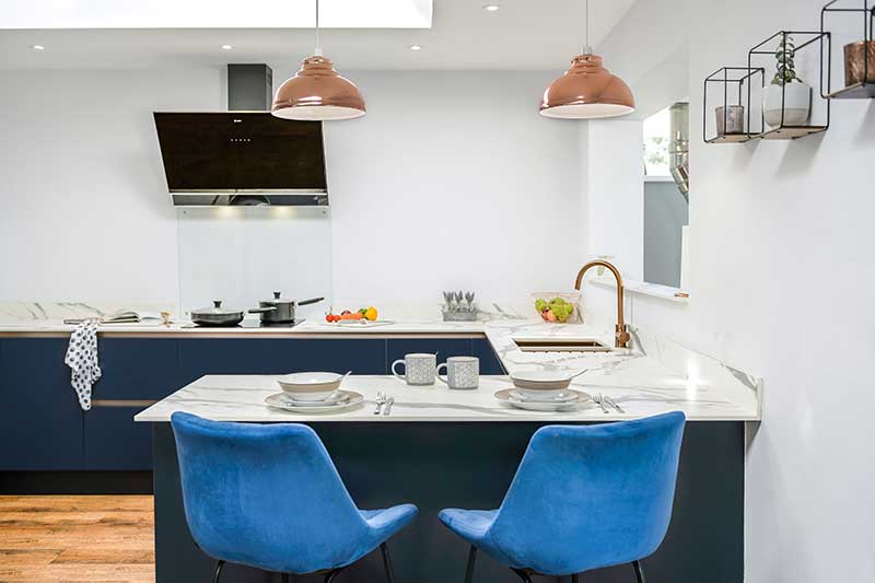 Copper pendant lights go well in this contemporary handleless navy blue kitchen